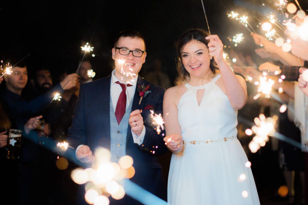 Bride and groom cheering and laughing with wedding sparklers