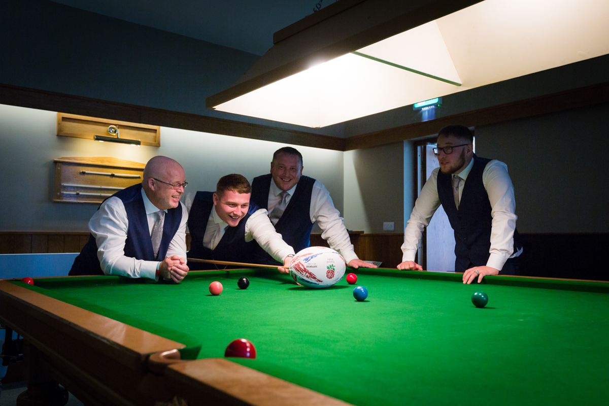 groom and groomsmen playing pool whilst getting ready photographed by Arley House and Gardens Wedding Photographer