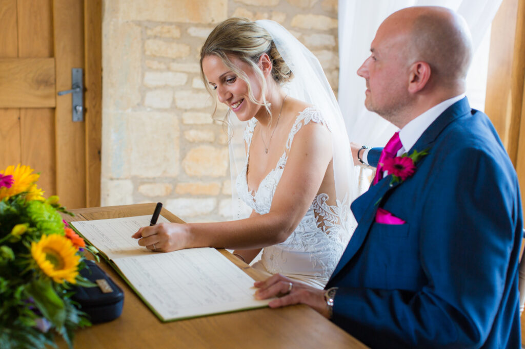 bride signing the register in her weddin g ceremony at the abrn at upcote
