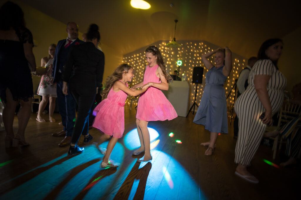 children spinning and dancing at a wedding at the barn at upcote
