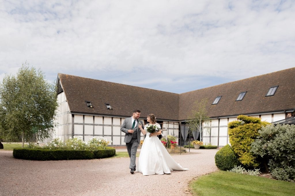 couple walking in their wedding venue grounds toasting a glass of champagne