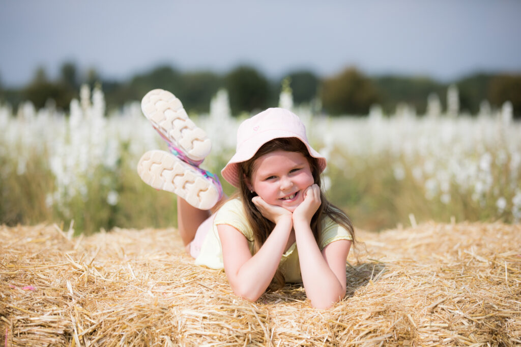 girl smiling at camera on hay bale at pershore confetti fields