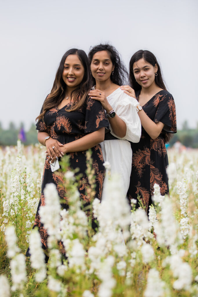 family of three women looking at camera in white confetti fields flowers