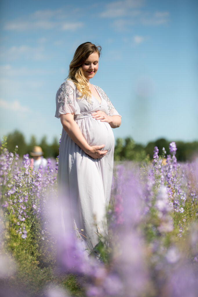 pregnant lady in grey dress standing in purple flower field