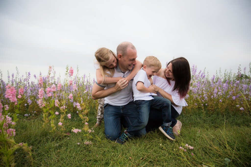 family of four hugging on the ground in the pershore confetti fields
