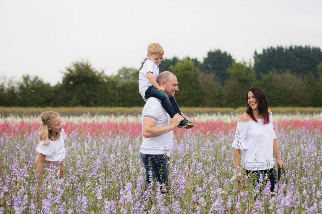 family of four walking through colourful purple flowers at pershore confetti fields