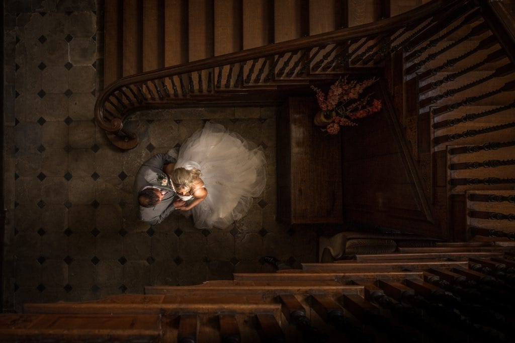 bride and groom standing at bottom of wooden staircase taken from above