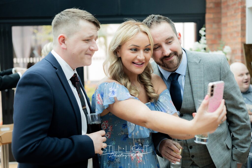 guests arriving at redhouse barn on autumn wedding day smiling and taking selfie