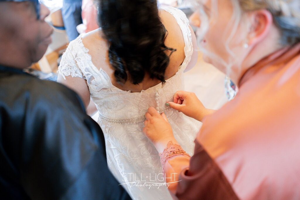 back of brides dress being fastened getting ready for wedding at redhouse barn