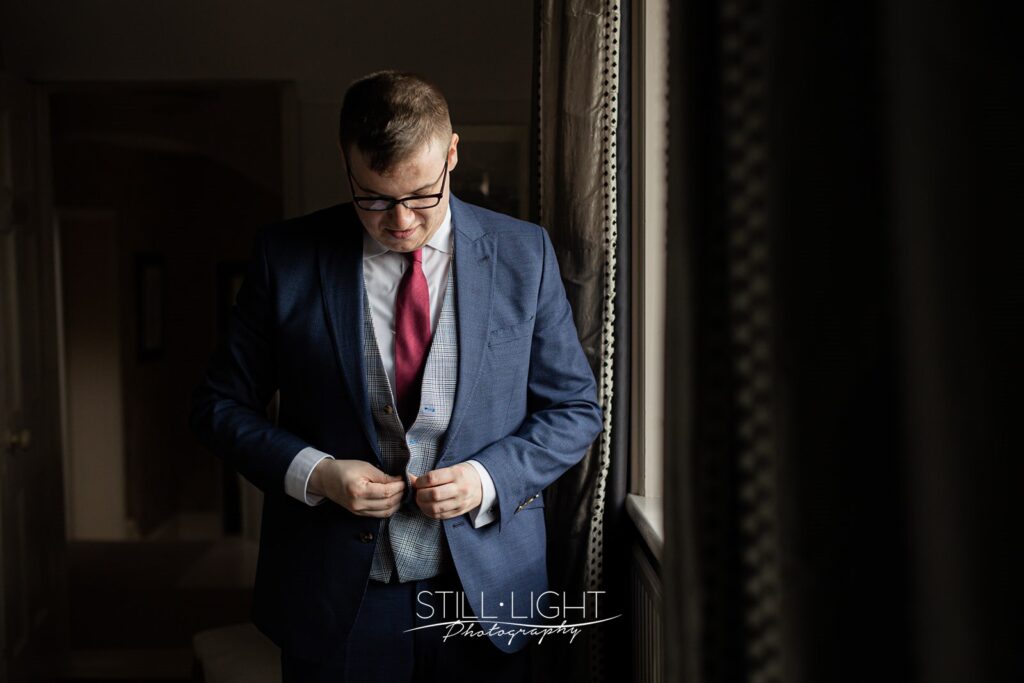 groom portrait by window getting ready for wedding day in the farmhouse at wotton park