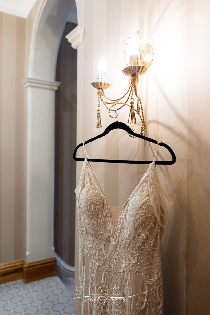 vintage wedding dress hanging on light fitting at brockencote hall