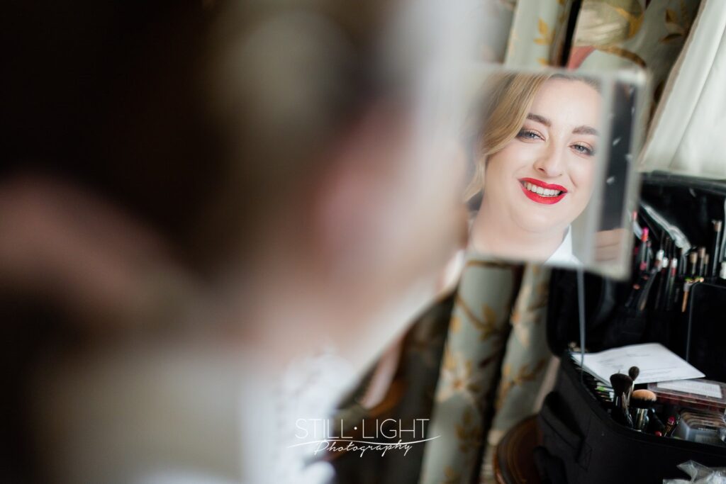 bride looking into mirror gettign ready for her wedding day
