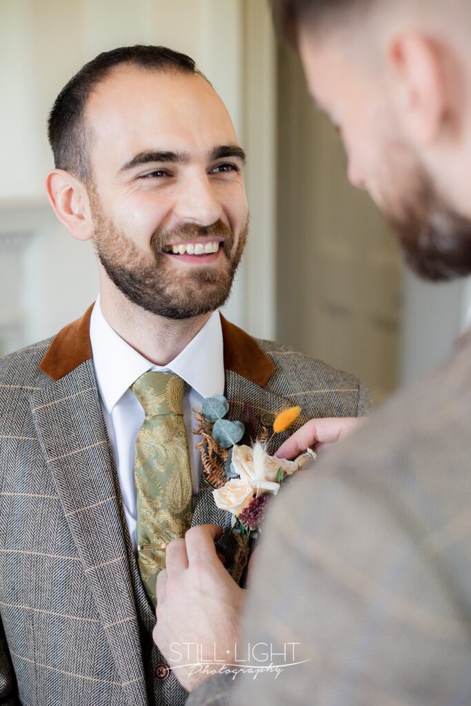 groom having buttonhole fitted for vintage wedding at brockencote hall