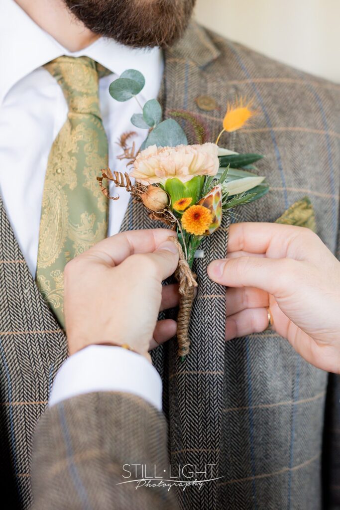 groom having buttonhole fitted for vintage wedding at brockencote hall