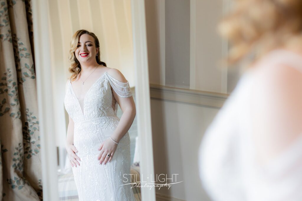 bride ready for her wedding day looking into mirror wearing vintage dress and red lipstick