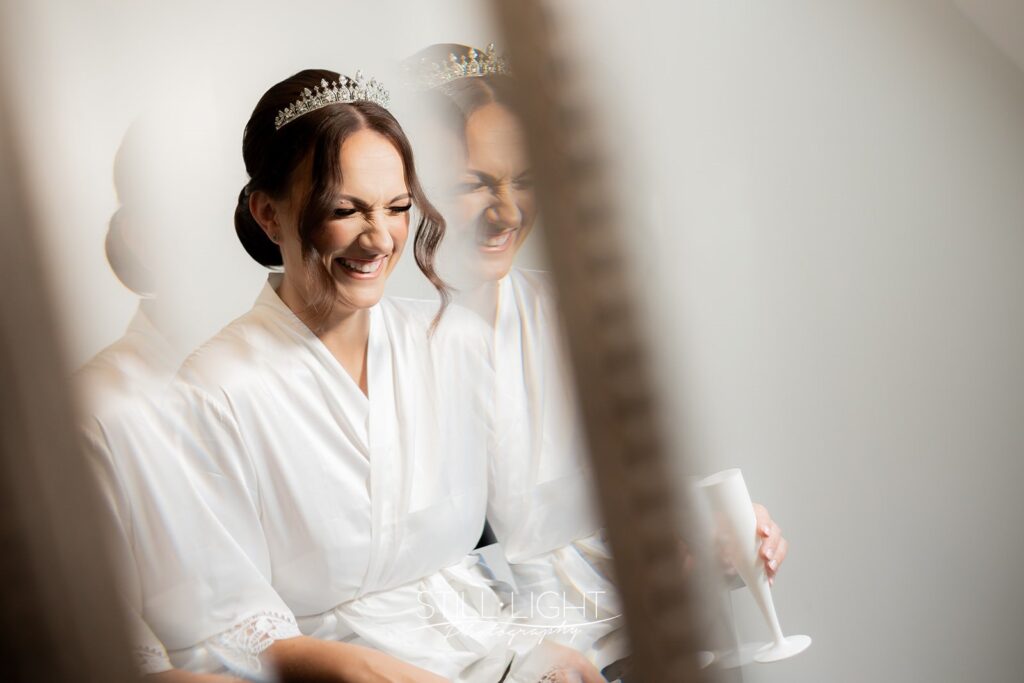bride laughing photogrpahed through mirror at stanbrook abbey on winter wedding day
