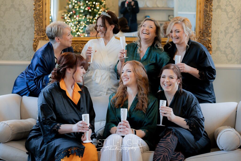 bride and bridesmaids laughing togehter on sofa in brides manor at stanbrook abbey hotel