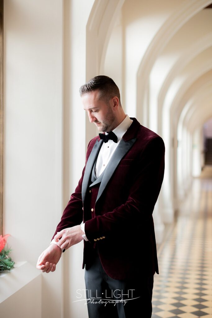 groom adjusting his cufflinks in the cloisters at stanbrook abbey hotel on winter wedding day