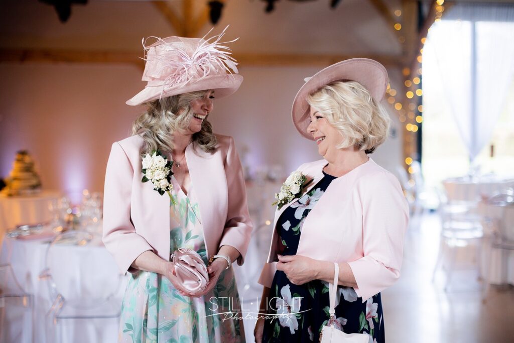 mums on wedding day at redhouse barn wearing pastel pink colour hats and jackets