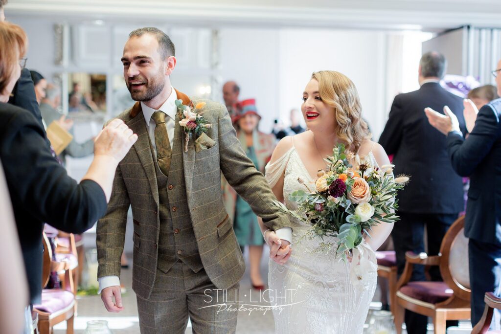 bride and groom exit up the aisle in brockencote hall after their vintage wedding ceremony