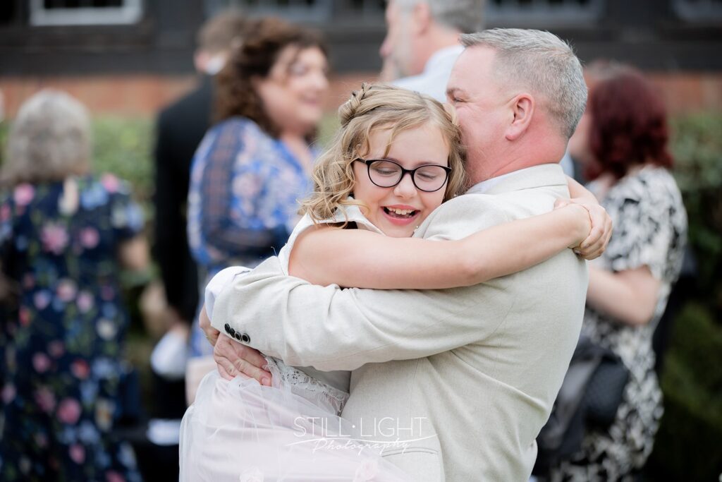 flowergirl hugs her dad during relaxed drinks reception at hogarths stone manor
