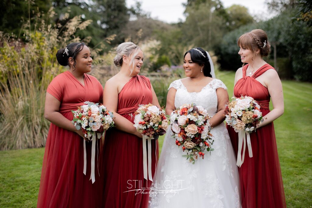 bride and briadesmaids smiling at each other in gardens at redhouse barn