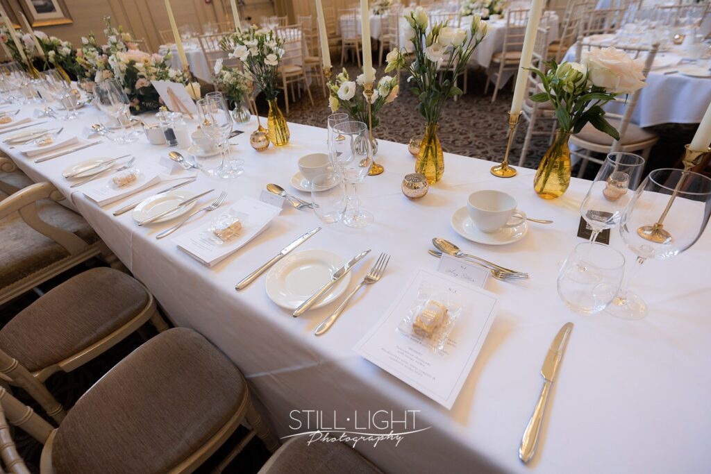 st anne's room set up for a wedding breakfast with cream chairs, vibrant flowers and gold cutlery