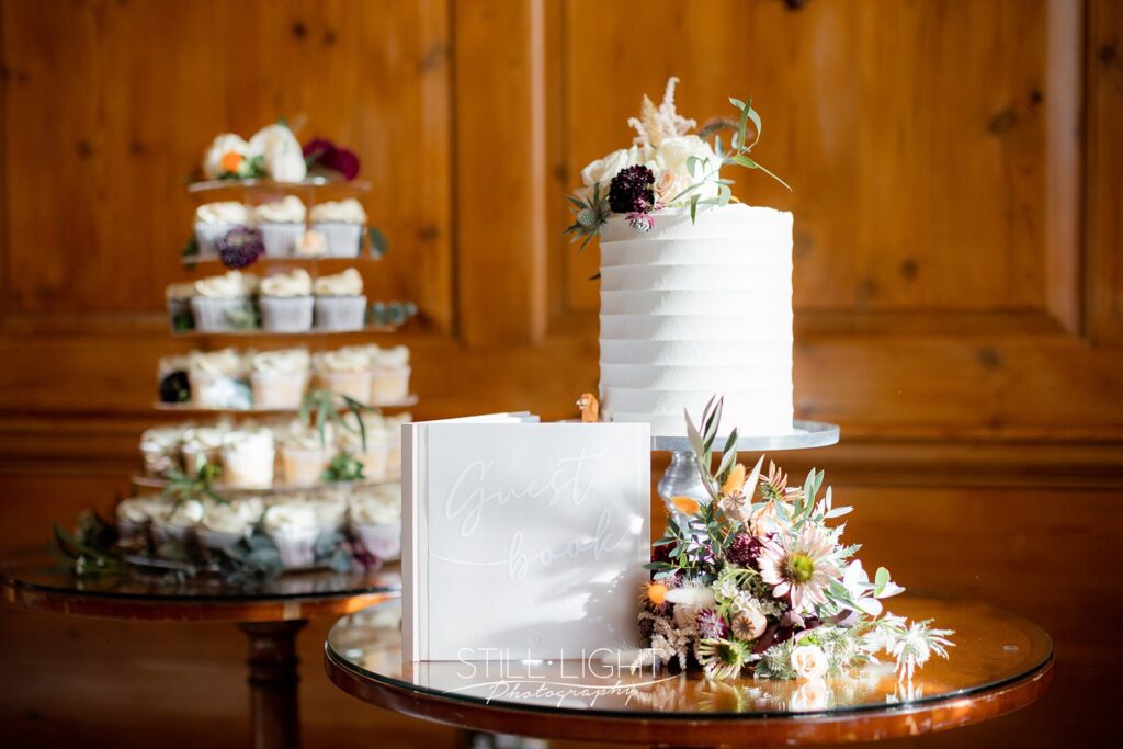 white wedding cake with orange and purple flowers next to it