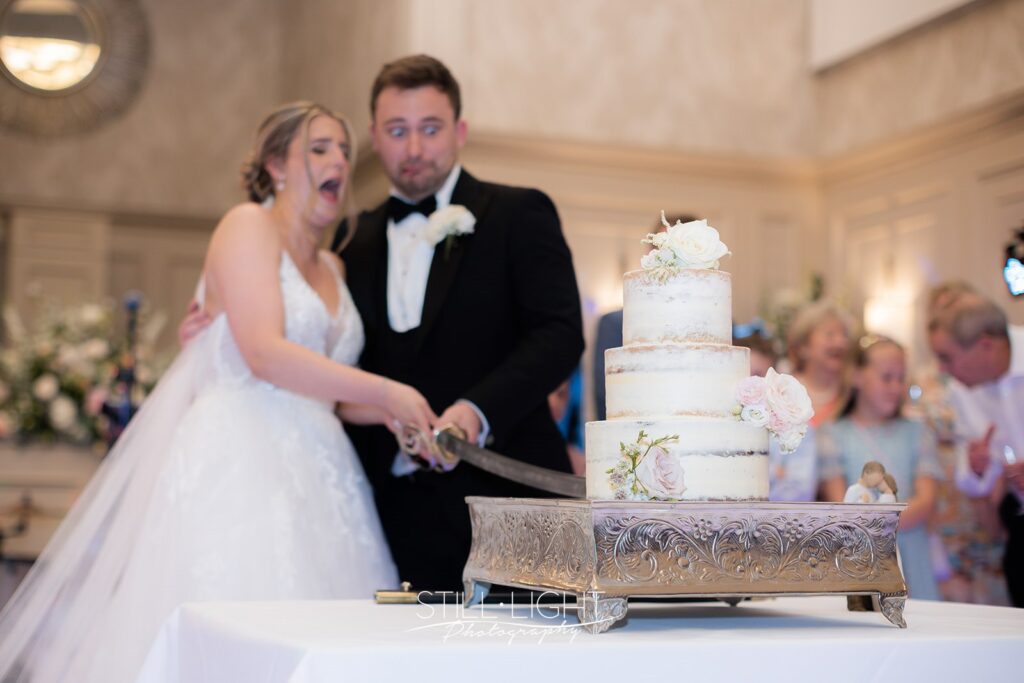 bride and groom during cutting of the cake with a sword at stanbrook abbey