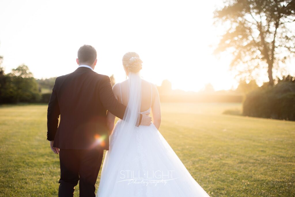 bride and groom at sunset walking away from camera on their summer wedding day at stanbrook abbey