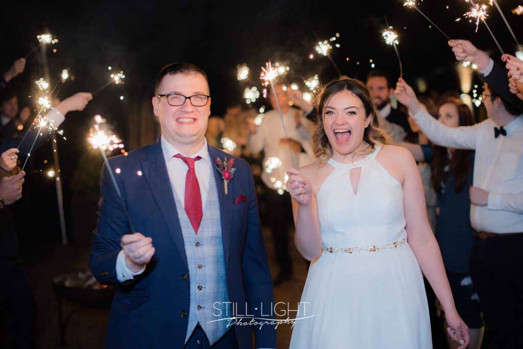 bride and groom surrounded by guests with sparklers held high