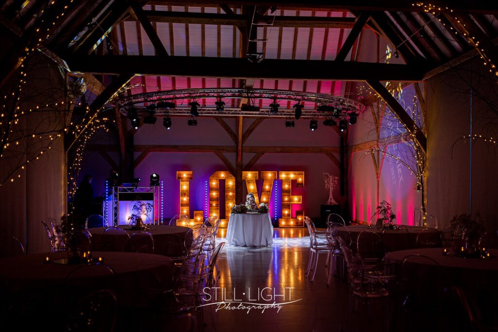 love letters against wall lighting up weding cake on dancefloor at redhouse barn