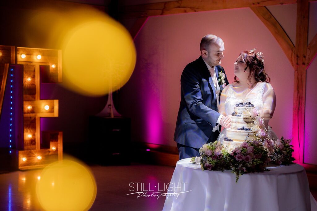 couple cutting their wedding cake on the dancefloor at redhouse barn