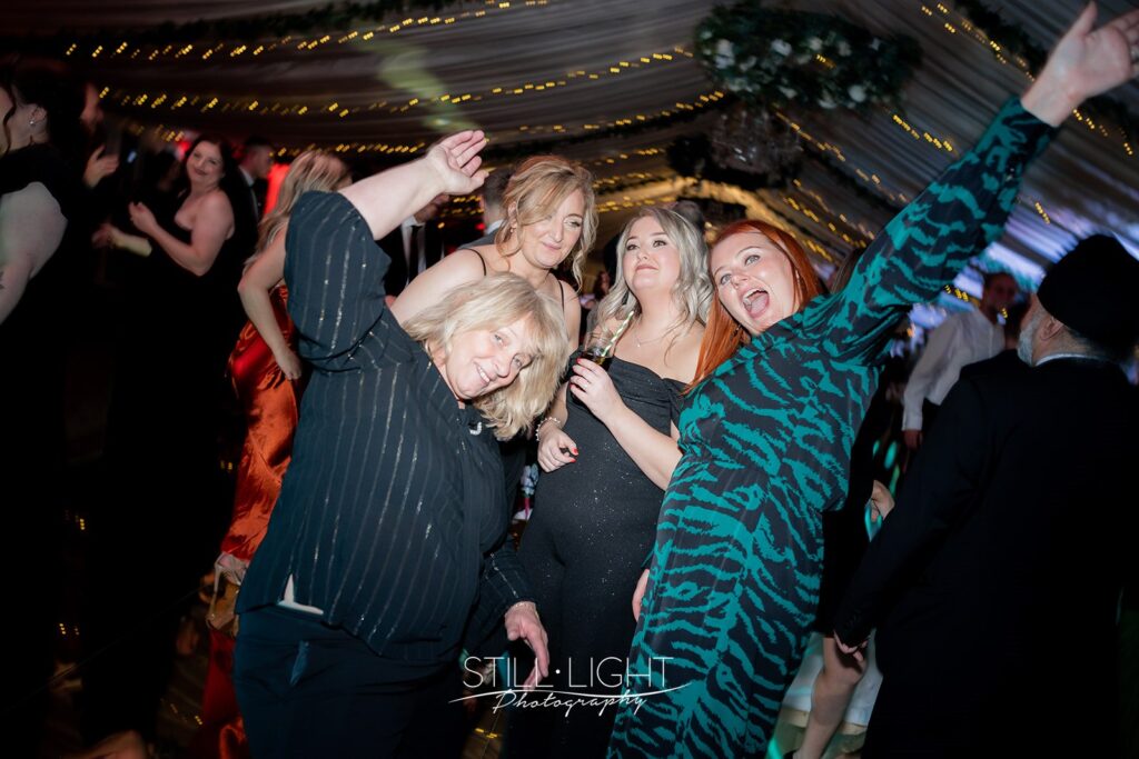 wedding guests on the dancefloor lauhging and holding their arms up