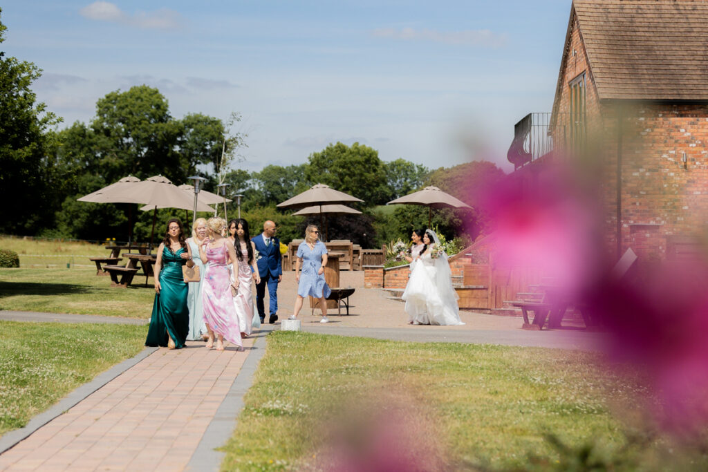 bridal party walking towards camera on their way to the lakeside civil ceremony at wootton park