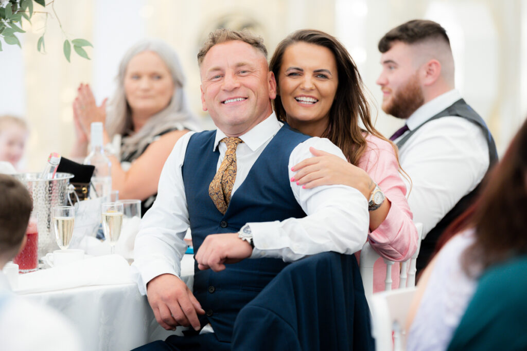 guests smiling at camera during wedding breakfast in the marquee at bordesley park on summer wedding day
