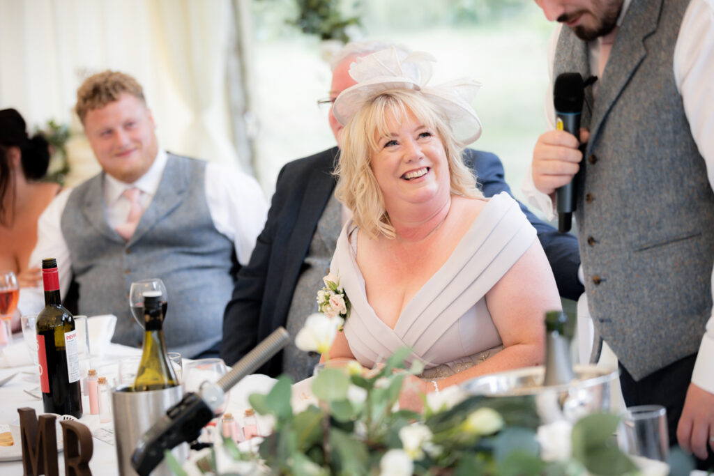 lady smiling during wedding breakfast in the marquee at bordesley park on summer wedding day