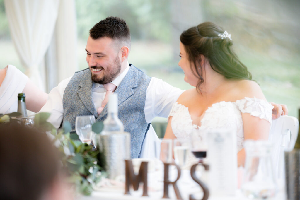 groom laughing during wedding breakfast in the marquee at bordesley park on summer wedding day