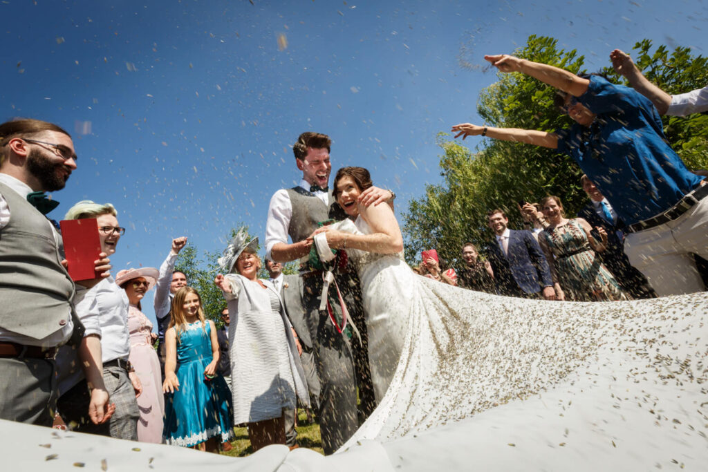 bride and groom laughing as guests throw confetti, taken from floor angle  by experienced wedding photographer