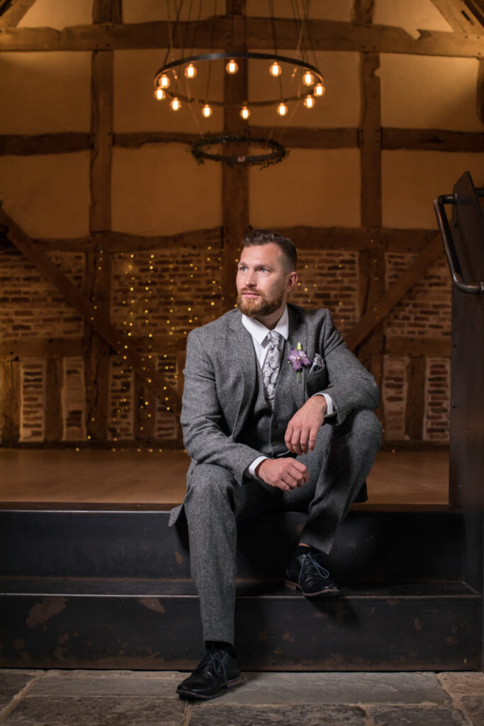 groom sitting wearing greay tweed suit photograph taken by experienced wedding photographer