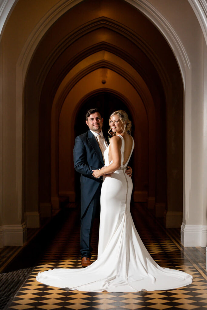 bride and groom standing in cloisters at stanbrook abbey on their wedding day, portrait taken by still light photography