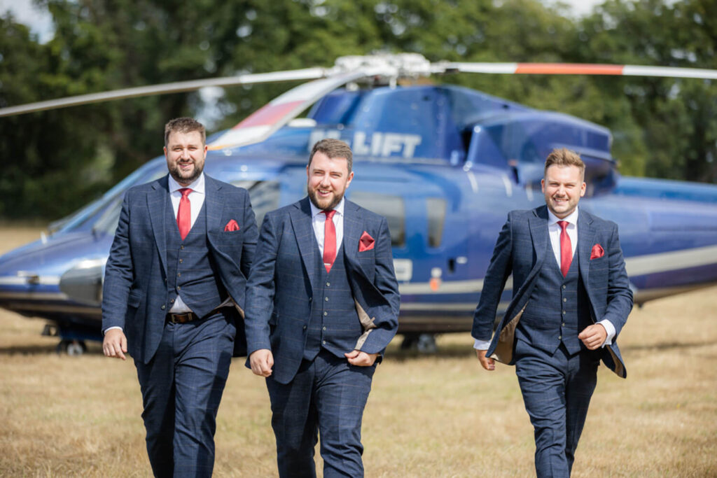 three men walking away from helicoptor after arriving at their wedding venue, photograph taken by experienced wedding photographer