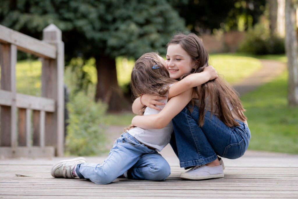 two sisters hugging in park during an outdoor family photography session in worcestershire