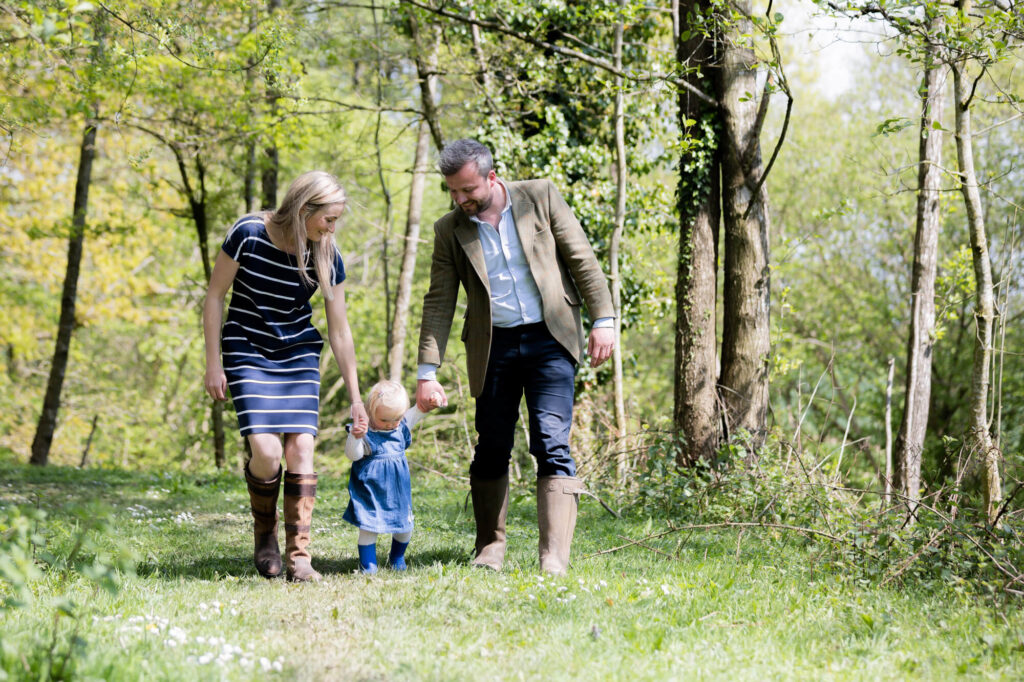 couple walking with young daughter through forest  during an outdoor family photography session in worcestershire