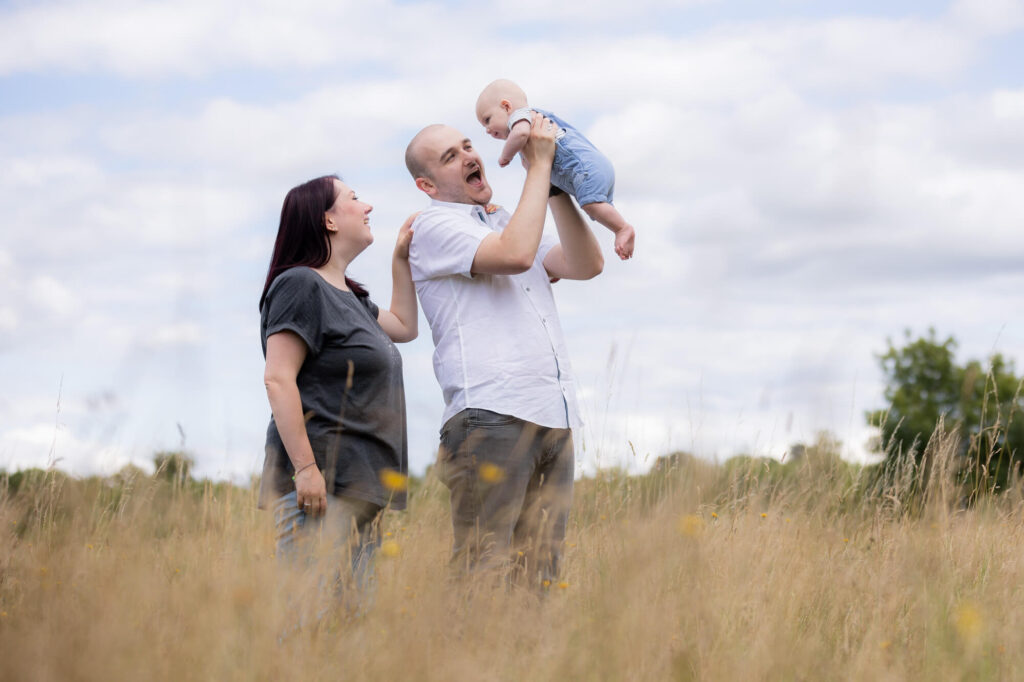 couple with baby in field during an outdoor family photography session in worcestershire