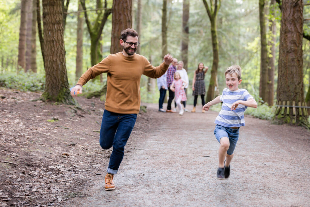 dad and son running towards camera in forest during an outdoor family photography session in worcestershire
