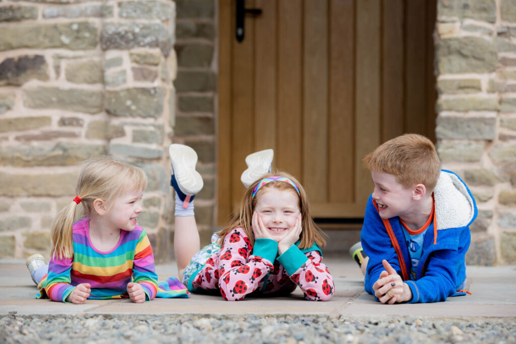 three children laying on floor during an outdoor family photography session in worcestershire