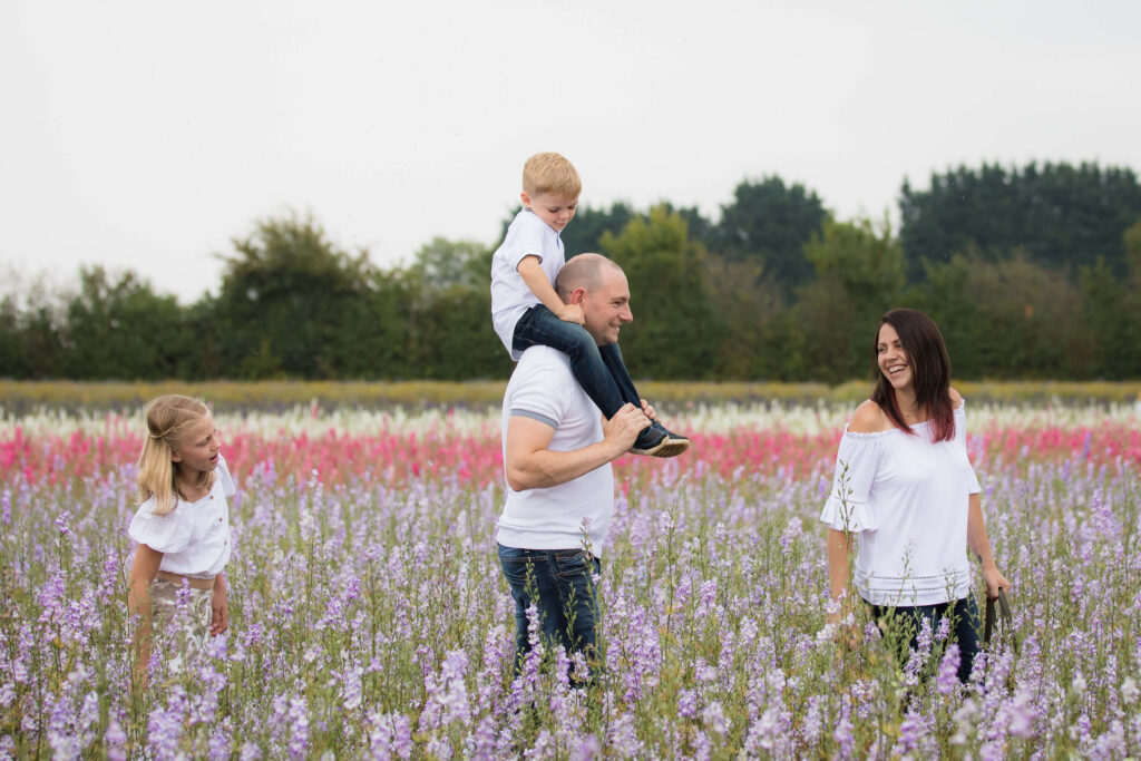 family of 4 with 2 children walking through purple flower fields during an outdoor family photography session in worcestershire