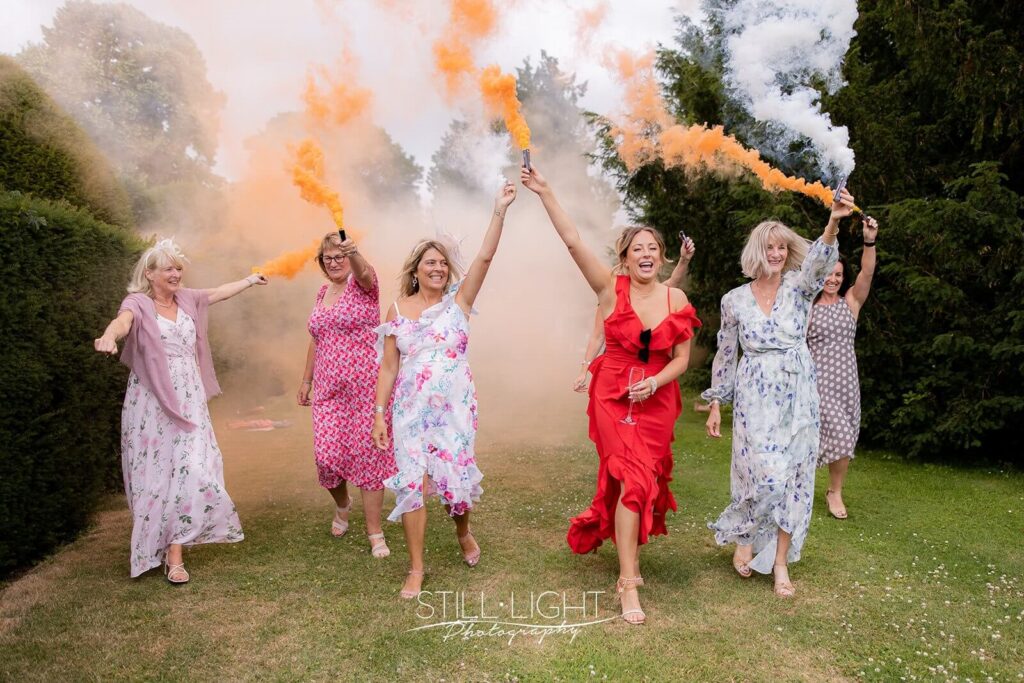 wedding guests running with orange smoke grenades