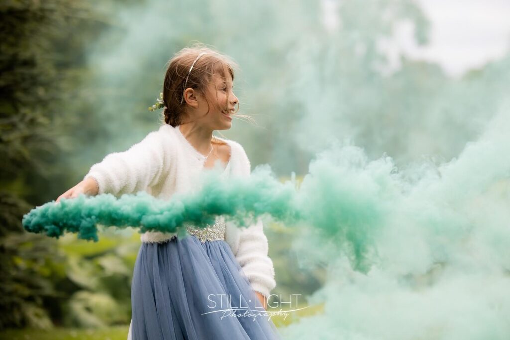 young girl laughing whilst holding greem smoke grenade